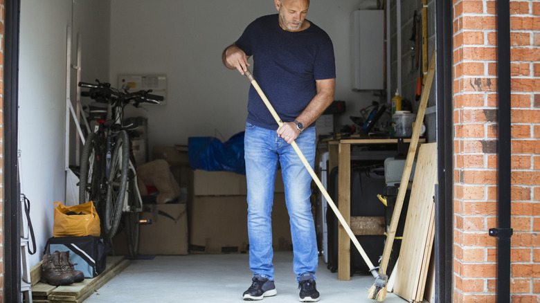 Man sweeping inside the garage of his home