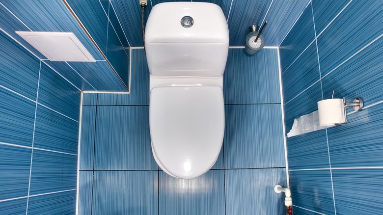 White toilet with closed lid in toilet with blue tiled wall and floor