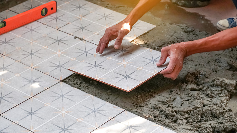 hands installing star-pattern floor tile squares