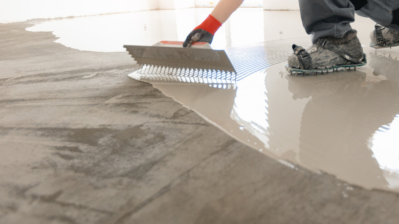 worker spreading self-leveling cement on floor