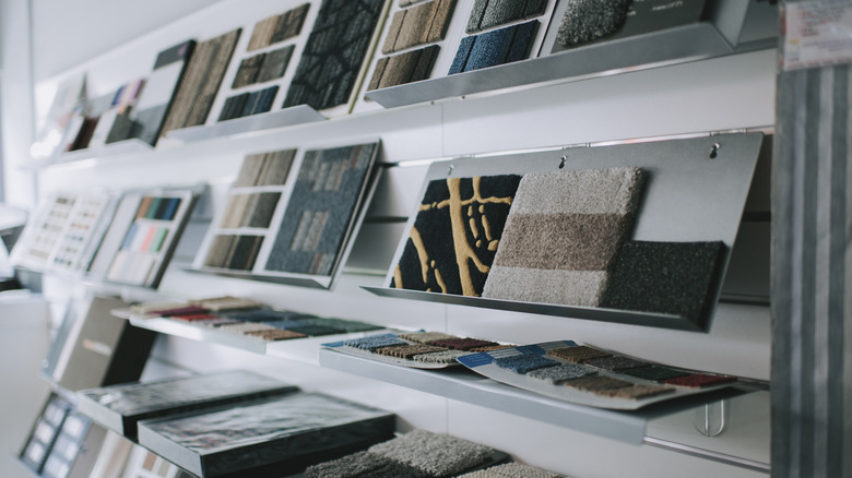 Patterned carpet samples are on display shelves in a store.