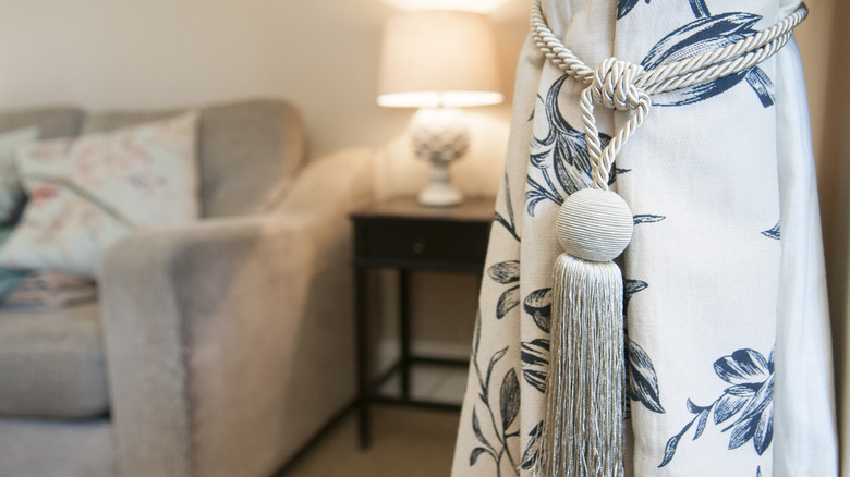 A close up of floral curtain tied with a tassel