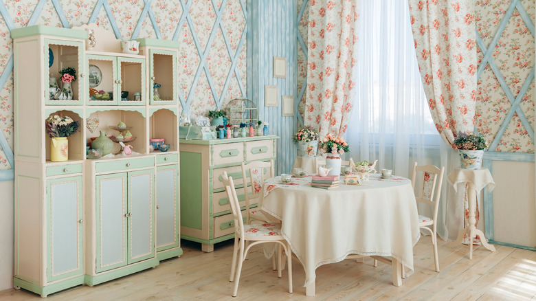 A pastel cottagecore room with floral curtains and wallpaper