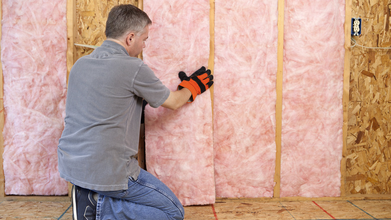 A man installing fiberglass insulation 