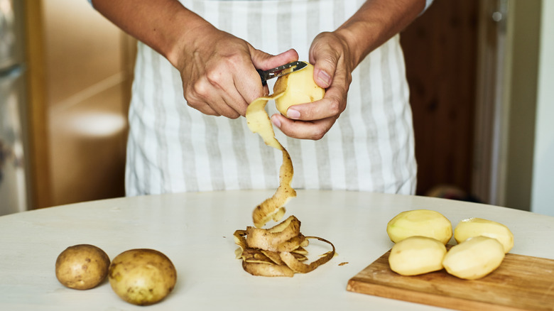 hands peeling potatoes