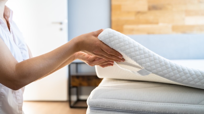 Woman adding topper to mattress