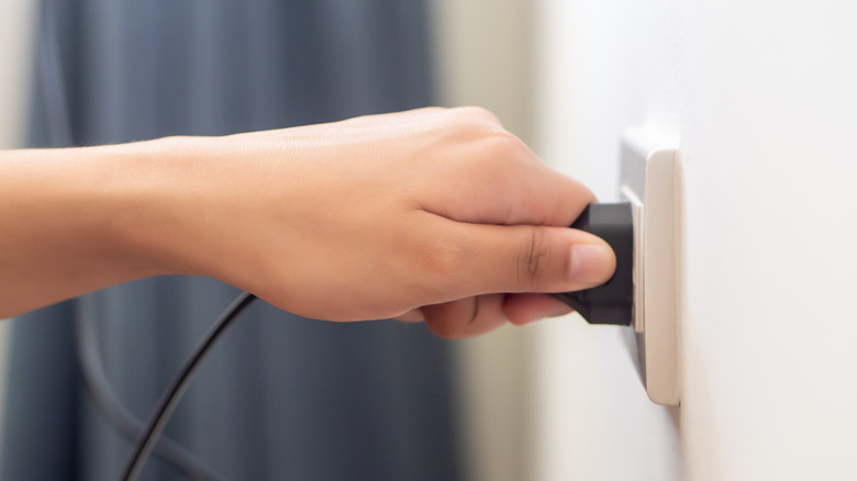 Person unplugging an appliance wire.