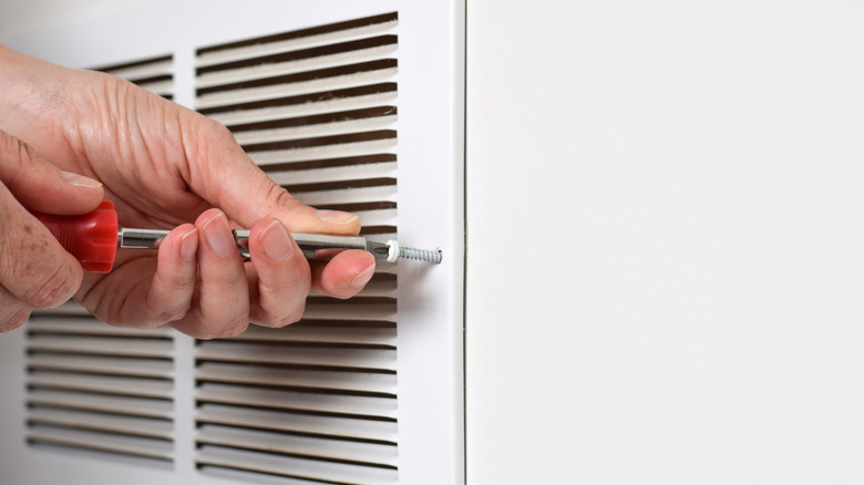 Person opening air vent with screwdriver