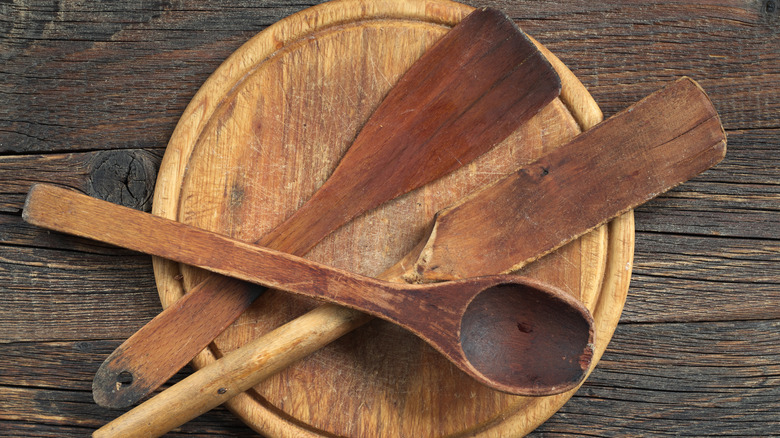 A collection of worn-out wooden utensils rest on a wooden platter