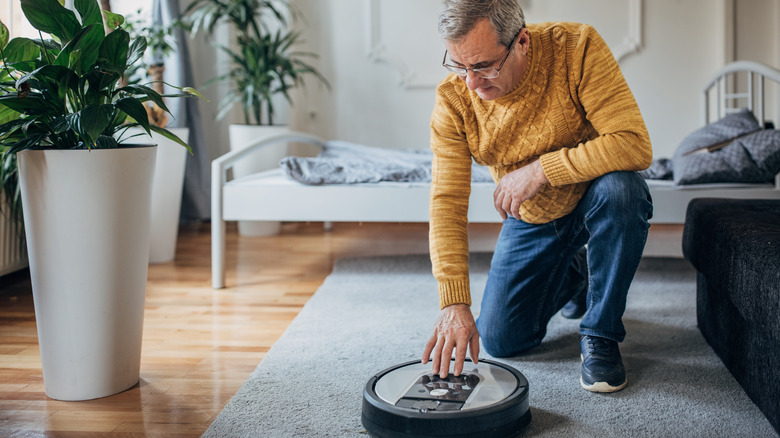 man touching robot vacuum