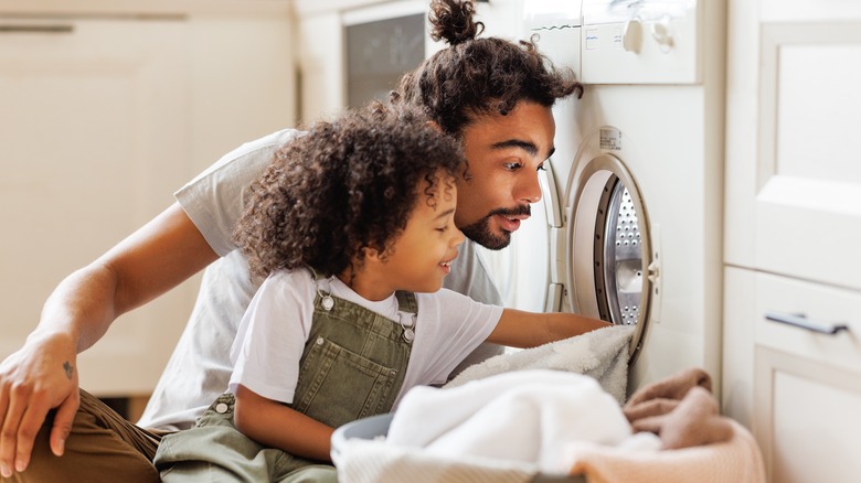 A father and son look inside a front-load washer