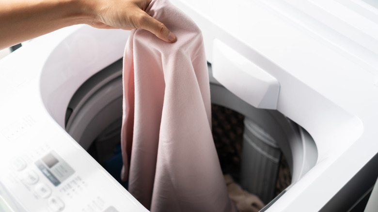 A person putting something into a top-load washer