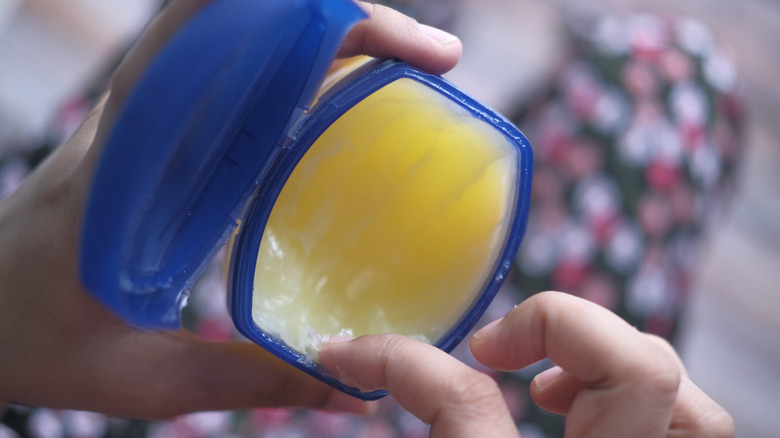 Person holding jar of petroleum jelly