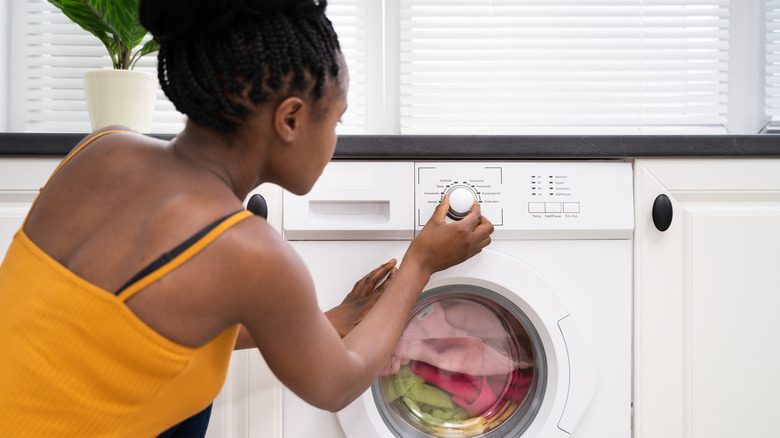 Person selecting washing machine cycle