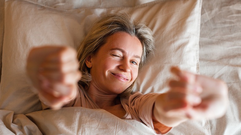 Woman stretches and winks in bed