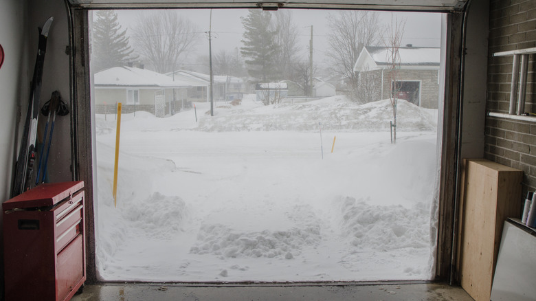 Garage with door raised to reveal snowy neighborhood