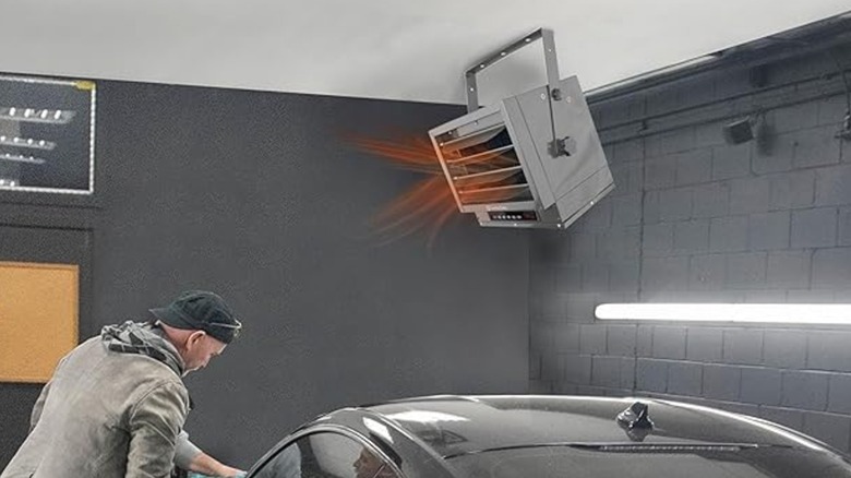 Comfort Zone garage heater mounted to ceiling above man working on car