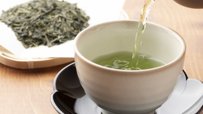 Pouring green tea and leaves
