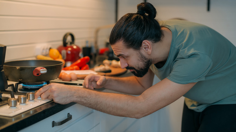 man cooking on gas stove