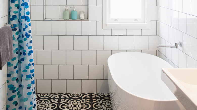 white tile shower with inset niche holding toiletries