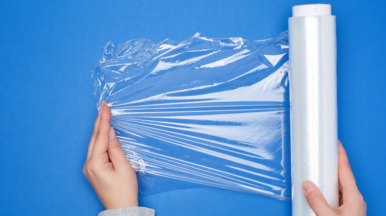 Hand unrolling plastic wrap