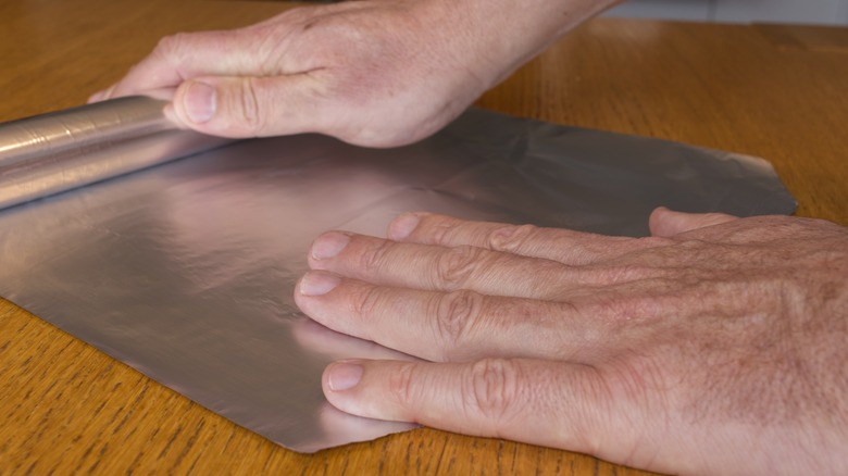 person ripping aluminum foil