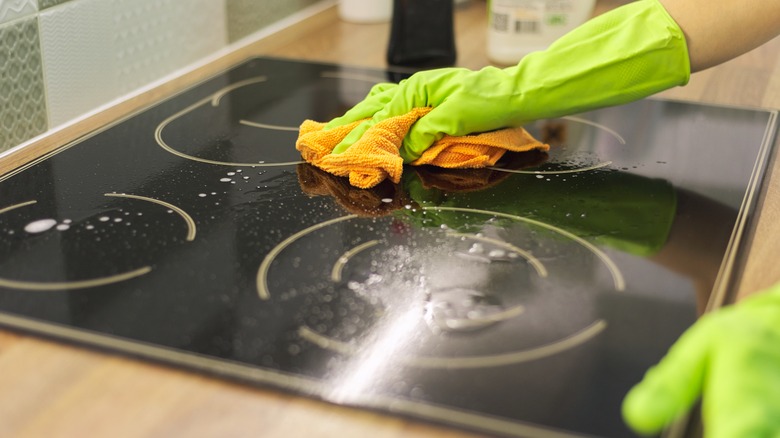 person cleaning glass stovetop