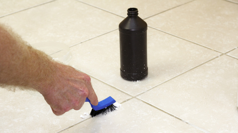 person scrubbing grout with brush
