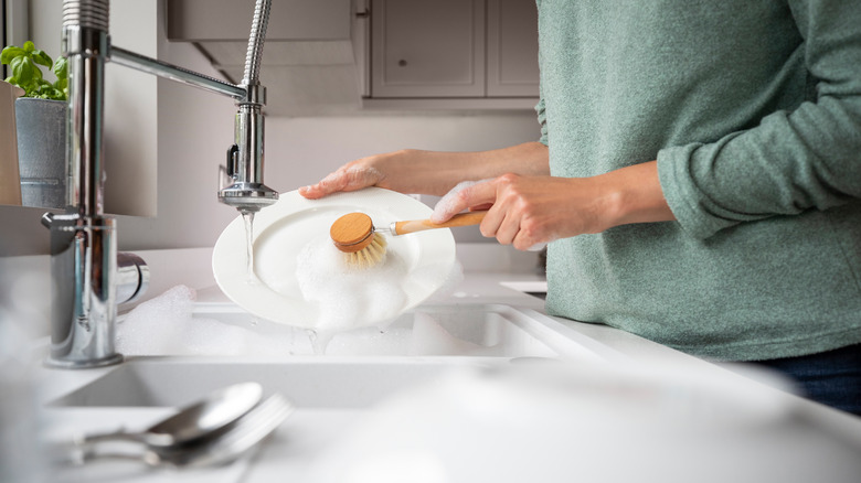 person cleaning with dish brush