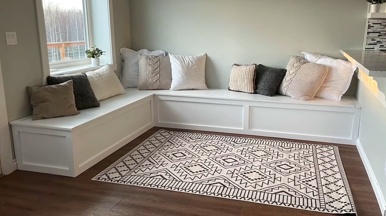 a white corner bench with pillows