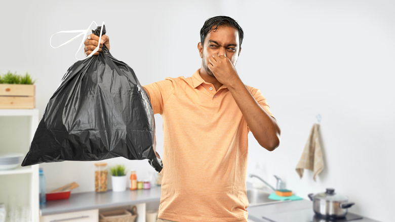 Man with trash holding nose