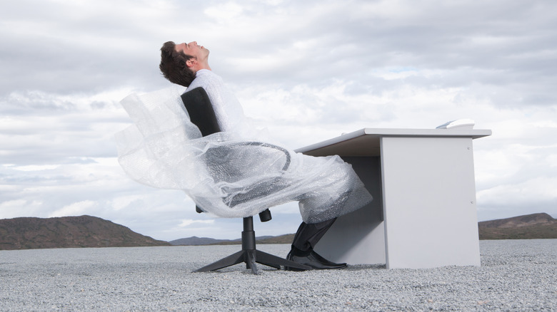 A man at a desk wrapped in bubble wrap 