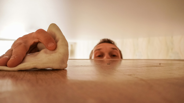 person wiping dust off shelf