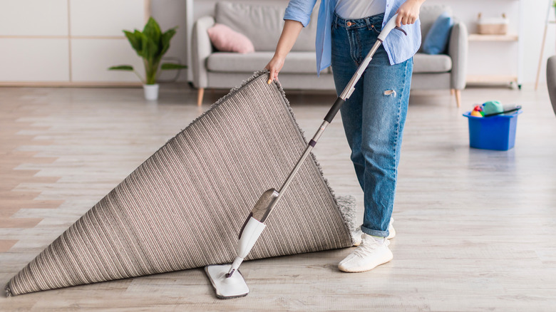 woman sweeping under rug