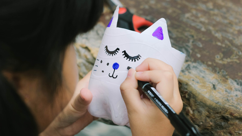 child decorating plastic pot