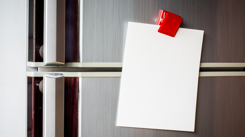 Plastic magnet clip holding piece of paper on fridge