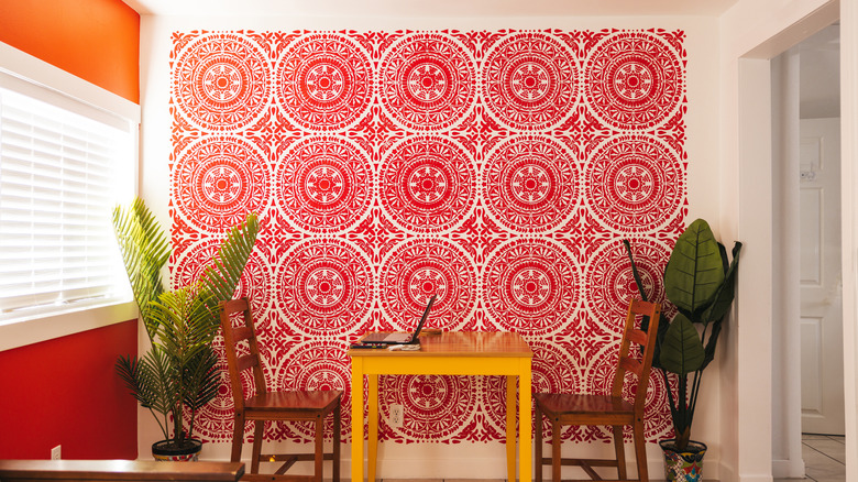 A vibrant room, featuring an orange wall, yellow table, and red circle-patterned wallpaper on one wall.