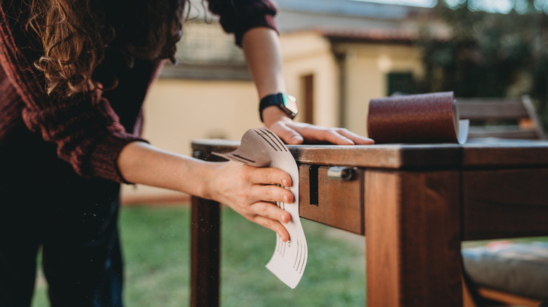 Someone sanding a wood table