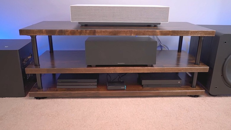 A DIY home entertainment center made from stained butcher block and painted pipes