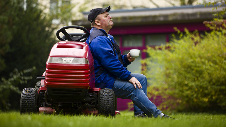 man sitting against lawn mower