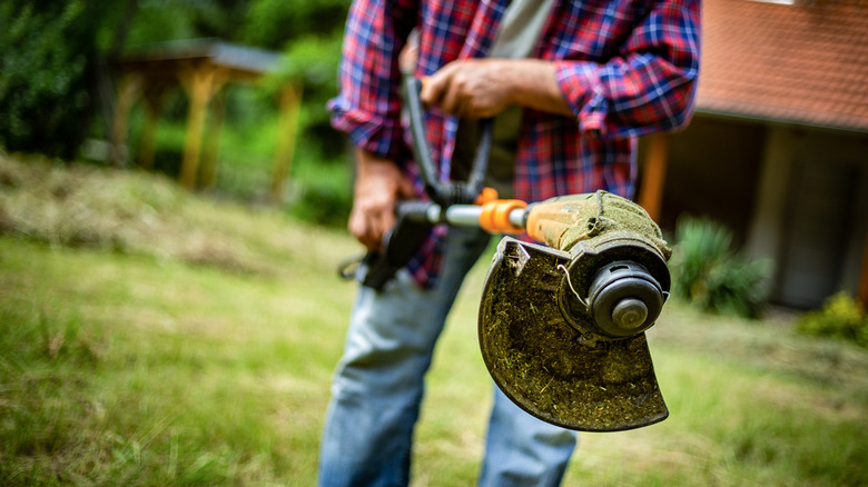 person holding weed whacker