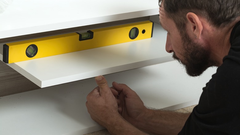 Man installing wooden shelf