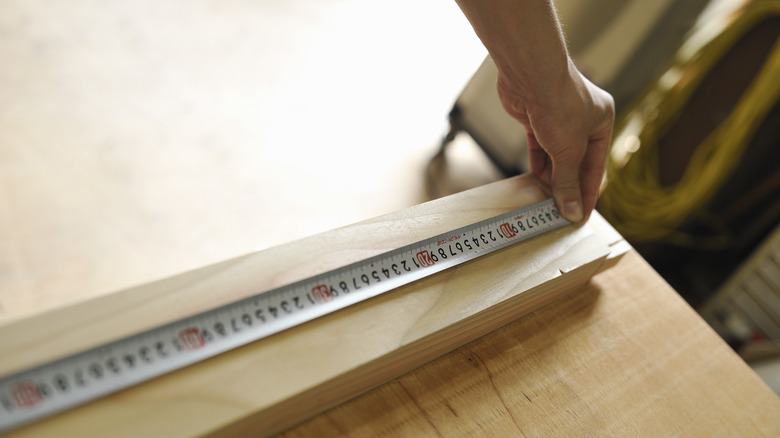 Person measuring wood board for project