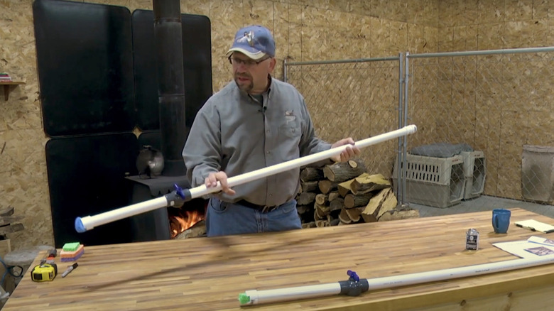 Man holds the PVC kill stick he built