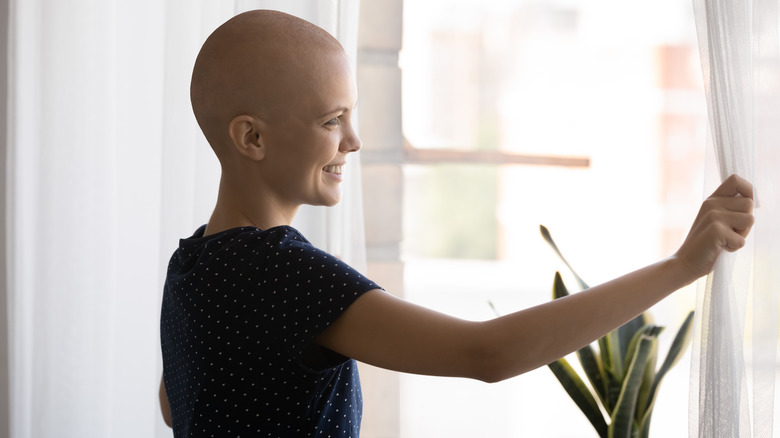 smiling woman opens curtains