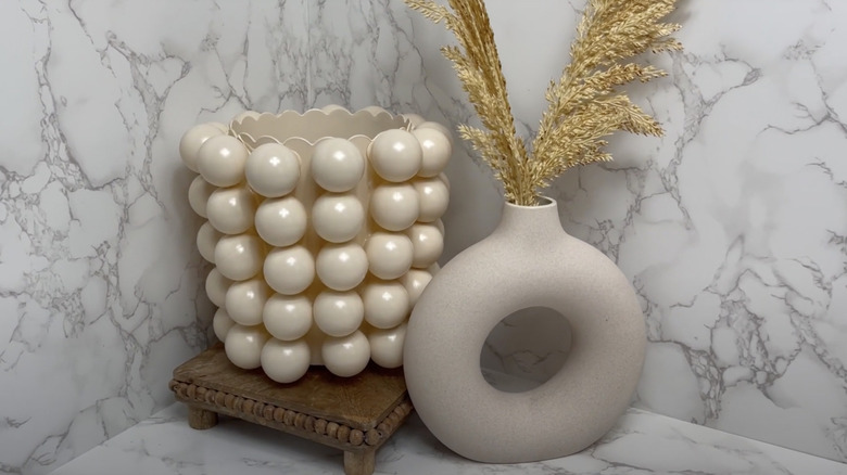 Two beige vases sit on a marble countertop