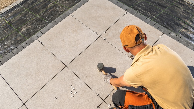 Worker installing patio tiles