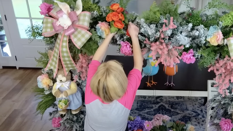 person attaching flowers to arch