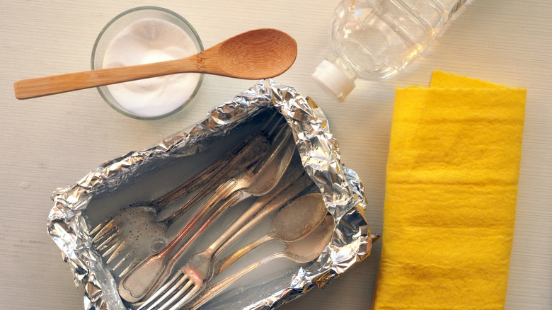 silverware in aluminum pan with cleaning ingredients and supplies