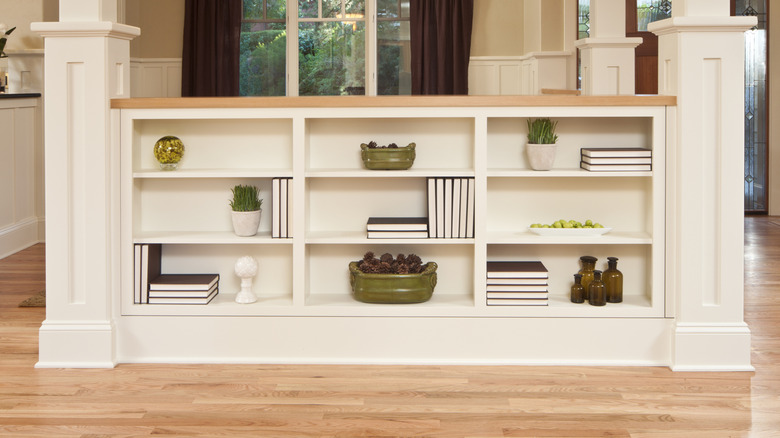 Half wall with shelves stocked with books and ornamental objects